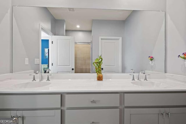 bathroom with double vanity, tiled shower, and a sink