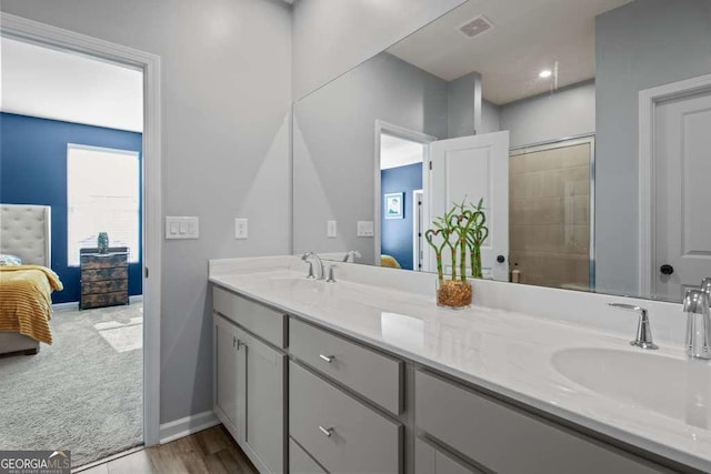 bathroom featuring connected bathroom, a tile shower, a sink, and double vanity