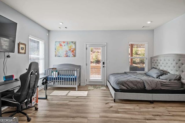 bedroom featuring access to outside, multiple windows, light wood-type flooring, and visible vents