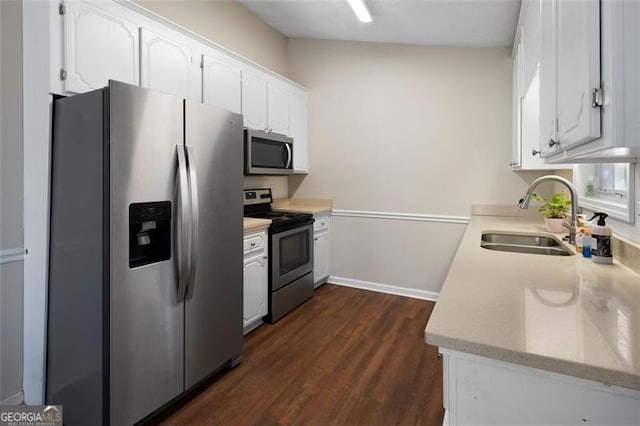 kitchen with a sink, white cabinets, light countertops, appliances with stainless steel finishes, and dark wood-style floors