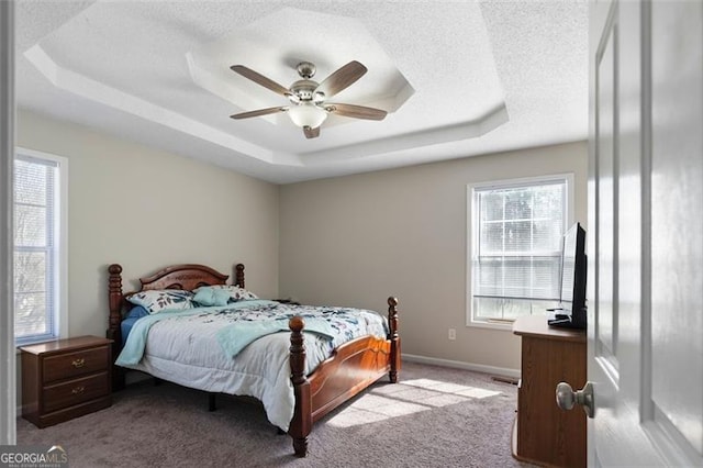 bedroom with light carpet, baseboards, a tray ceiling, and a textured ceiling