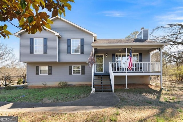 tri-level home featuring covered porch, a chimney, a front yard, and stairs