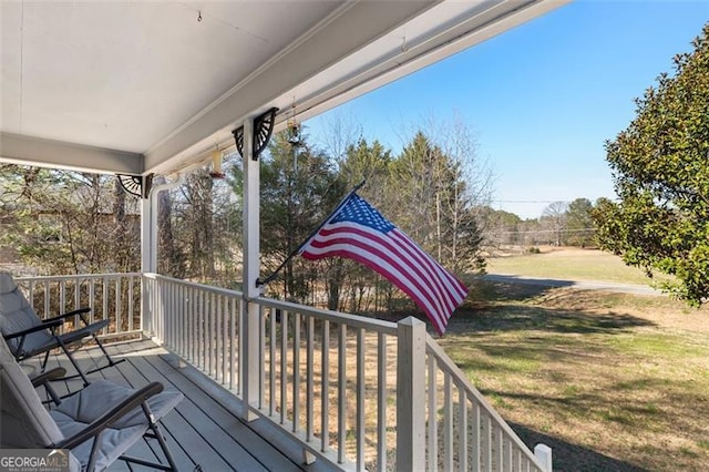 wooden deck with covered porch and a lawn