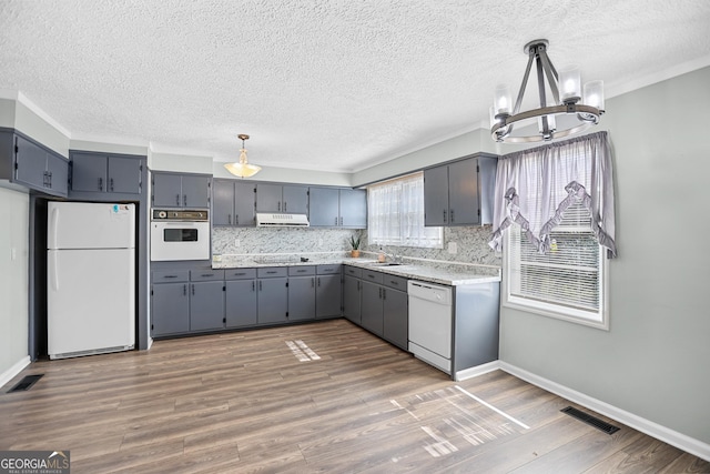 kitchen with white appliances, a sink, visible vents, and under cabinet range hood