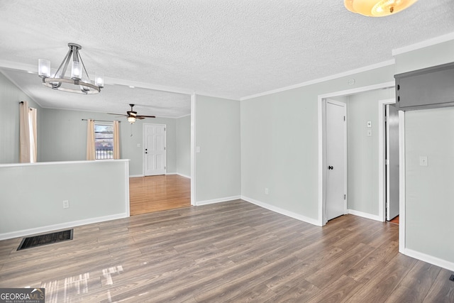 spare room featuring crown molding, visible vents, a textured ceiling, wood finished floors, and baseboards