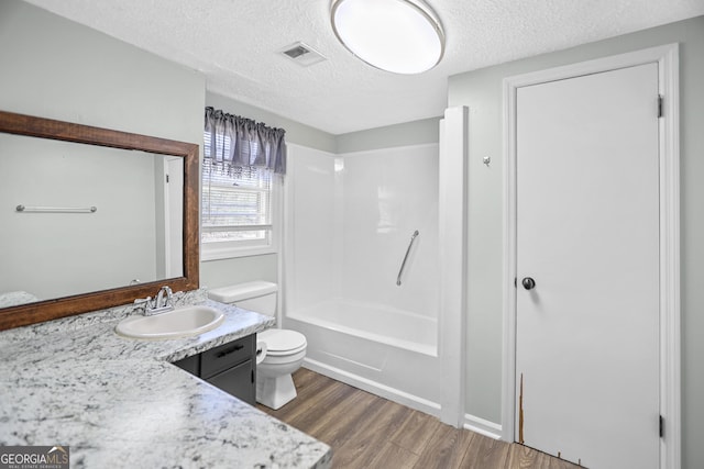 full bath featuring visible vents, toilet, wood finished floors, a textured ceiling, and vanity