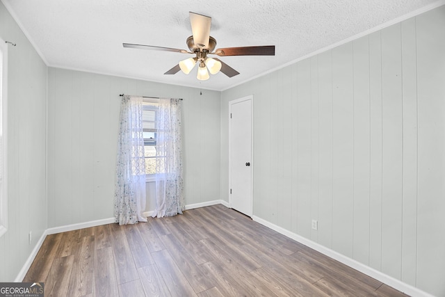 spare room featuring ornamental molding, a textured ceiling, baseboards, and wood finished floors