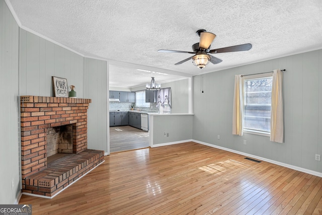 unfurnished living room with light wood-type flooring, a brick fireplace, visible vents, and ornamental molding