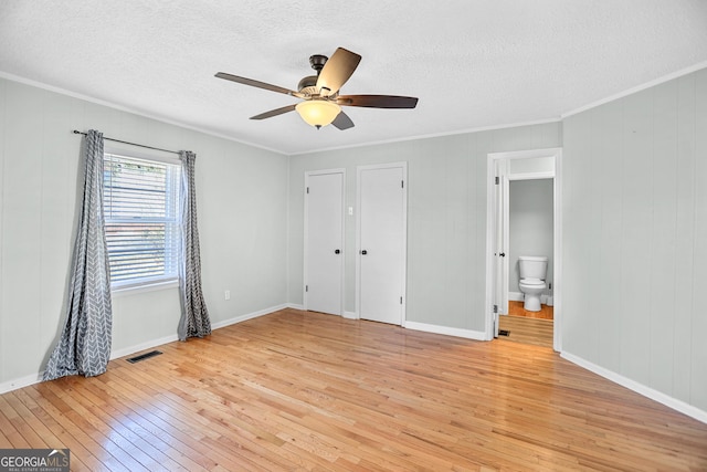 unfurnished bedroom featuring ornamental molding, light wood-style flooring, and visible vents