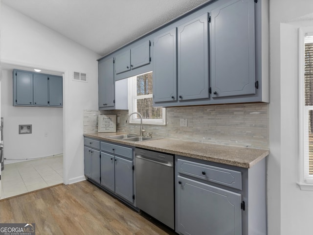 kitchen featuring visible vents, vaulted ceiling, light countertops, stainless steel dishwasher, and a sink