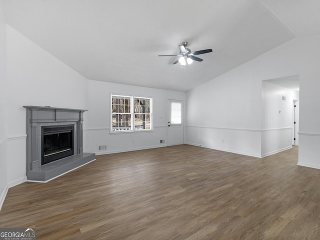 unfurnished living room featuring lofted ceiling, dark wood-style flooring, a fireplace with raised hearth, and visible vents