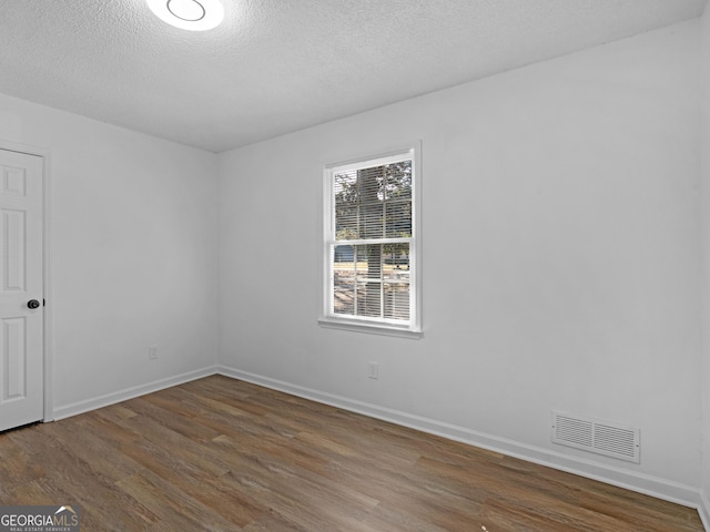 empty room featuring baseboards, a textured ceiling, visible vents, and dark wood-style flooring