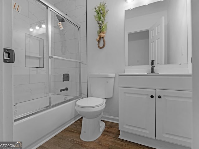 bathroom featuring enclosed tub / shower combo, toilet, wood finished floors, and vanity