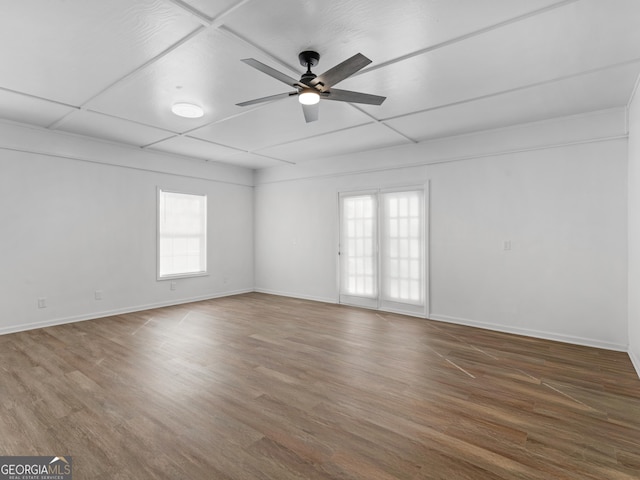 spare room with baseboards, wood finished floors, a wealth of natural light, and a ceiling fan