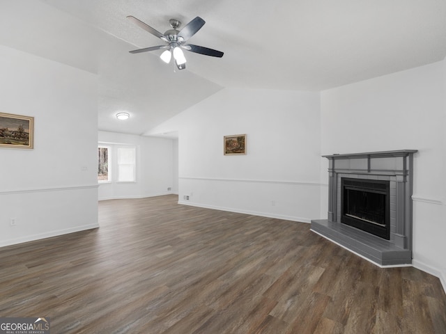 unfurnished living room with a fireplace with raised hearth, dark wood-type flooring, vaulted ceiling, and a ceiling fan