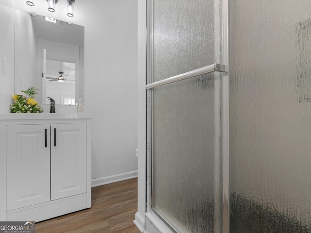 full bathroom with an enclosed shower, a ceiling fan, vanity, wood finished floors, and baseboards