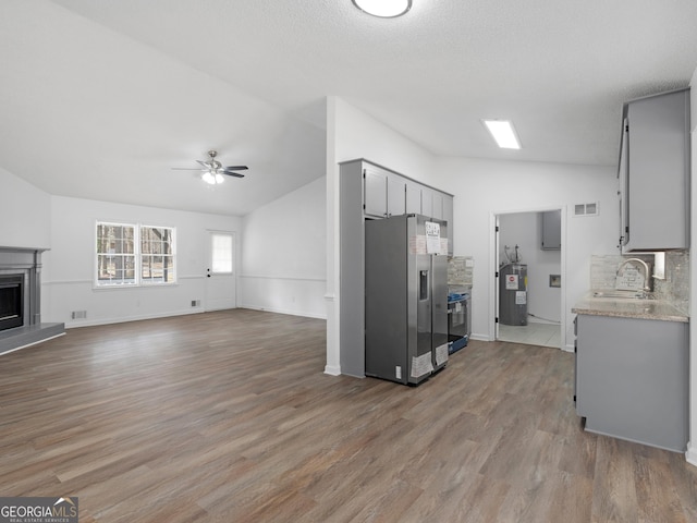 kitchen featuring a fireplace, lofted ceiling, open floor plan, electric water heater, and stainless steel fridge