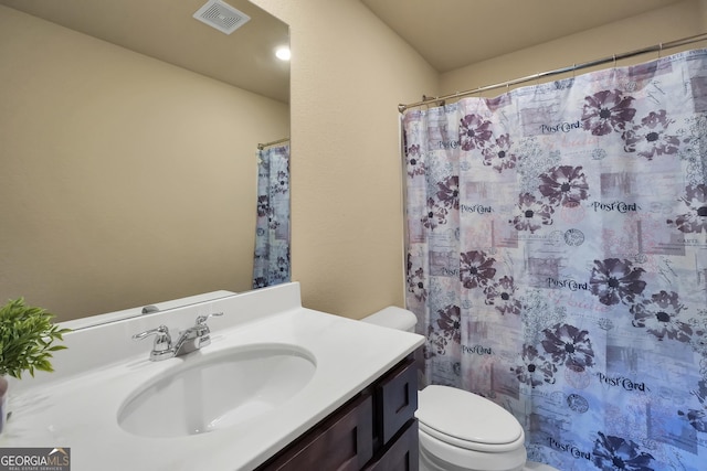 bathroom featuring a shower with shower curtain, visible vents, vanity, and toilet