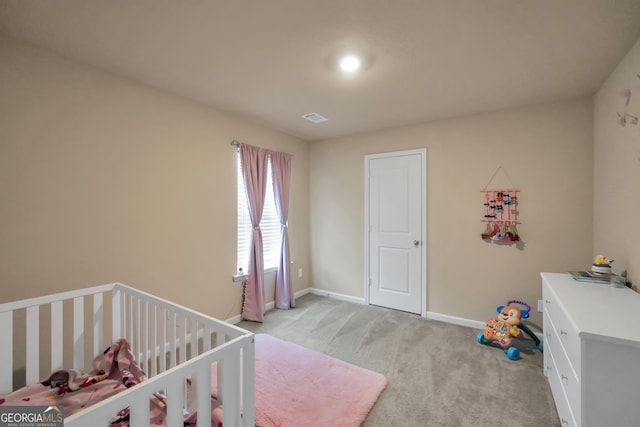 bedroom featuring a crib, baseboards, visible vents, and light colored carpet