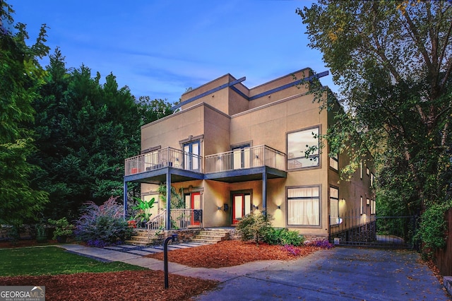 view of front of home with a balcony, a porch, and stucco siding