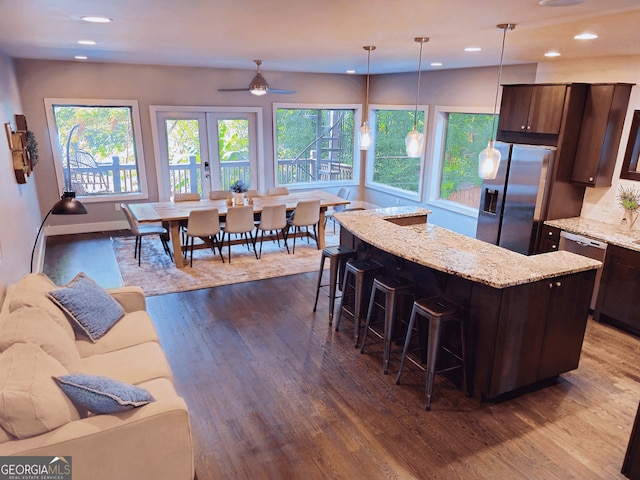 kitchen featuring dark wood-style floors, stainless steel appliances, dark brown cabinets, and a kitchen bar