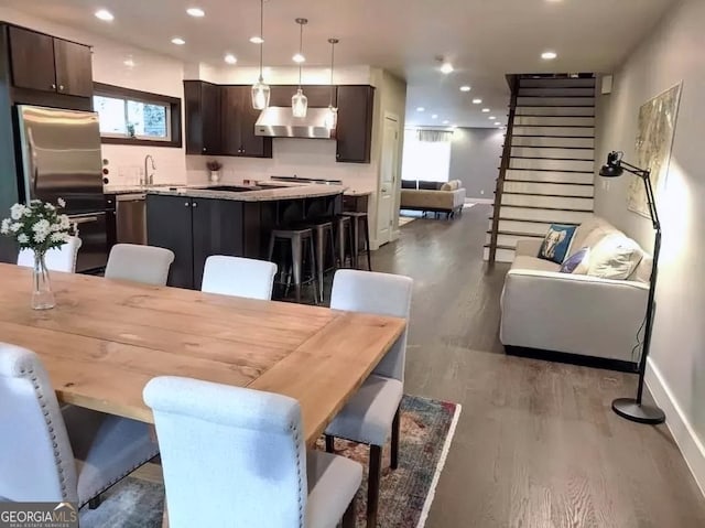 dining room featuring dark wood-type flooring, recessed lighting, baseboards, and stairs