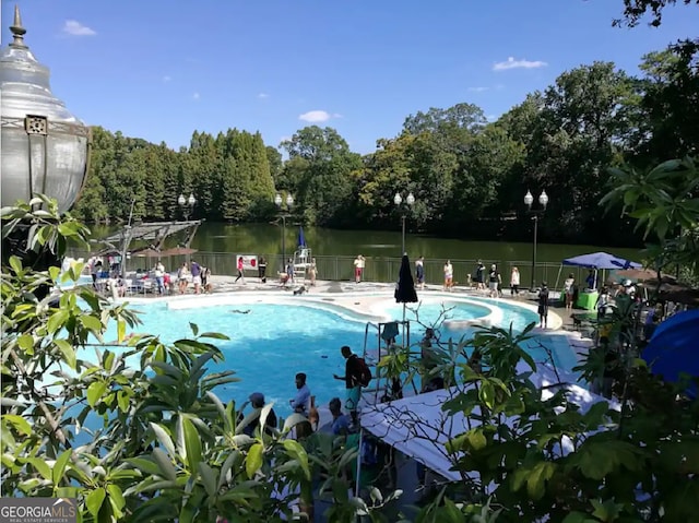 community pool featuring a water view, fence, and a patio