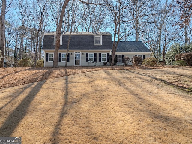 view of front of property with a shingled roof, a front lawn, and a gambrel roof