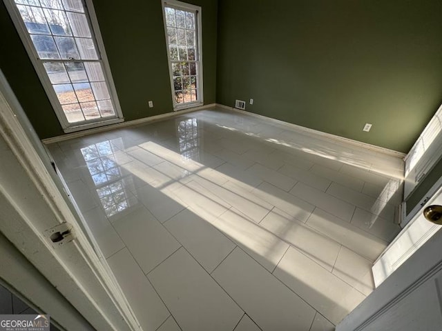 tiled empty room featuring visible vents and baseboards