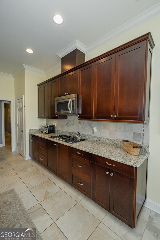 kitchen featuring baseboards, ornamental molding, appliances with stainless steel finishes, light stone countertops, and tasteful backsplash