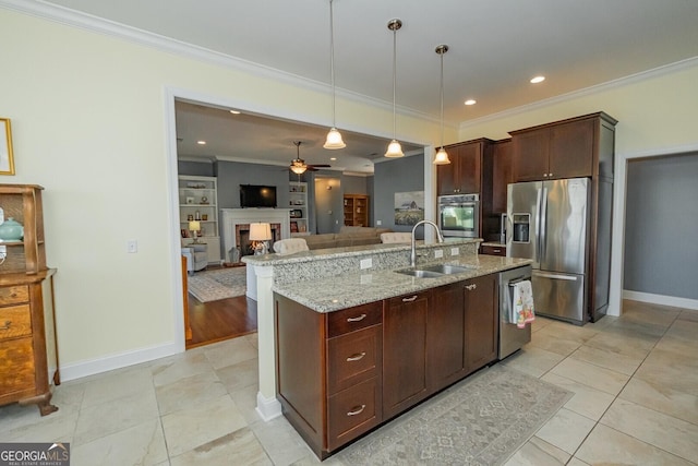 kitchen with a warm lit fireplace, stainless steel appliances, a sink, ornamental molding, and decorative light fixtures