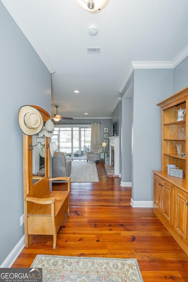 interior space featuring visible vents, crown molding, baseboards, and wood finished floors