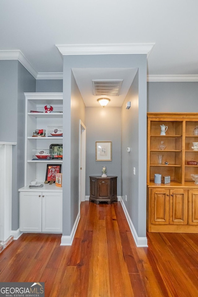 hall with crown molding, wood finished floors, visible vents, and baseboards