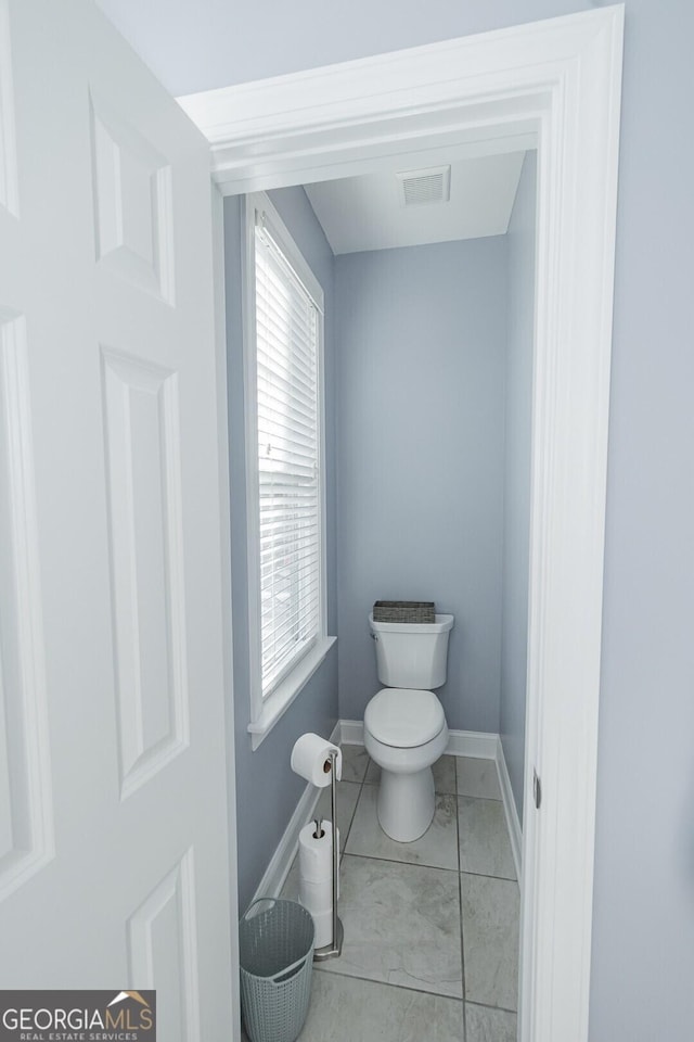 bathroom with tile patterned flooring, baseboards, visible vents, and toilet