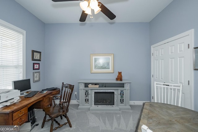 home office with carpet floors, ceiling fan, a premium fireplace, and baseboards