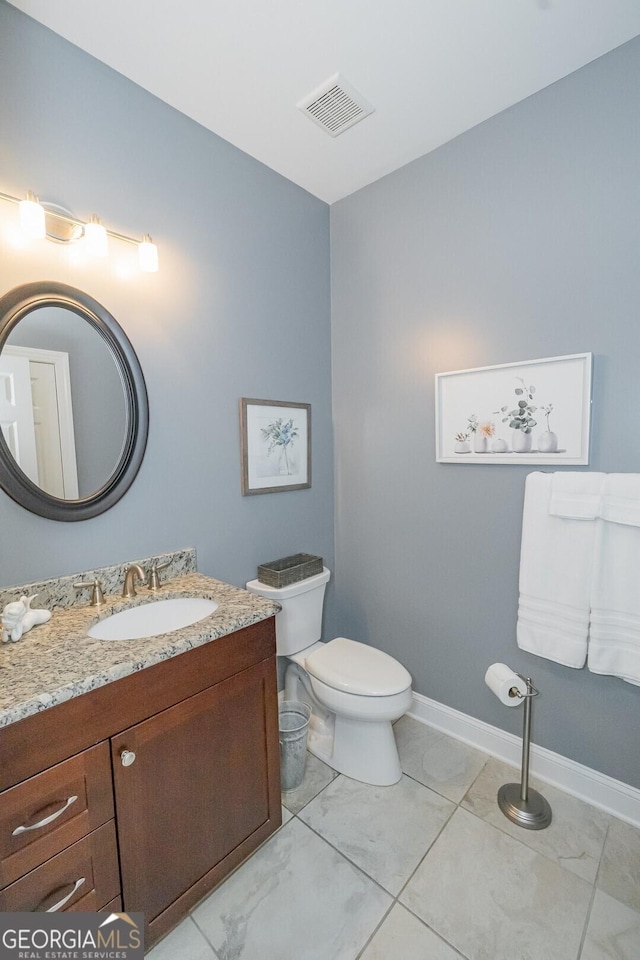 bathroom with toilet, vanity, visible vents, baseboards, and marble finish floor