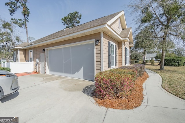 view of property exterior with a garage, fence, and concrete driveway