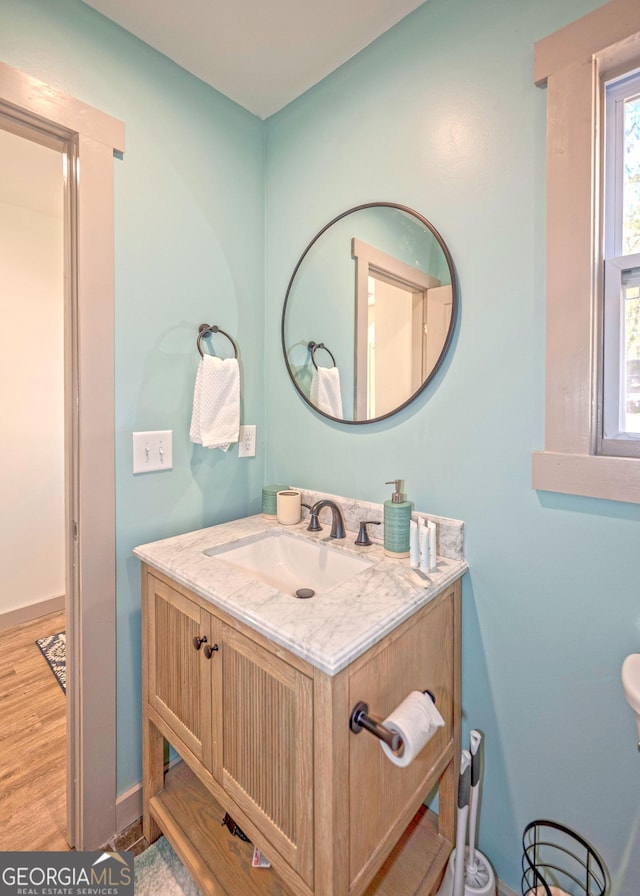 bathroom with baseboards, wood finished floors, and vanity