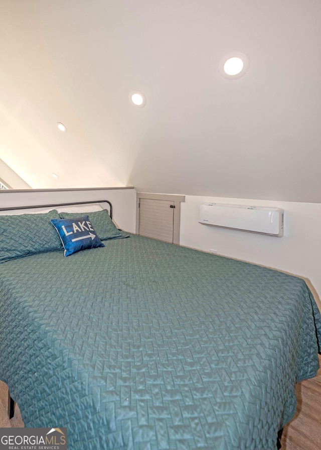 bedroom featuring lofted ceiling, an AC wall unit, wood finished floors, and recessed lighting