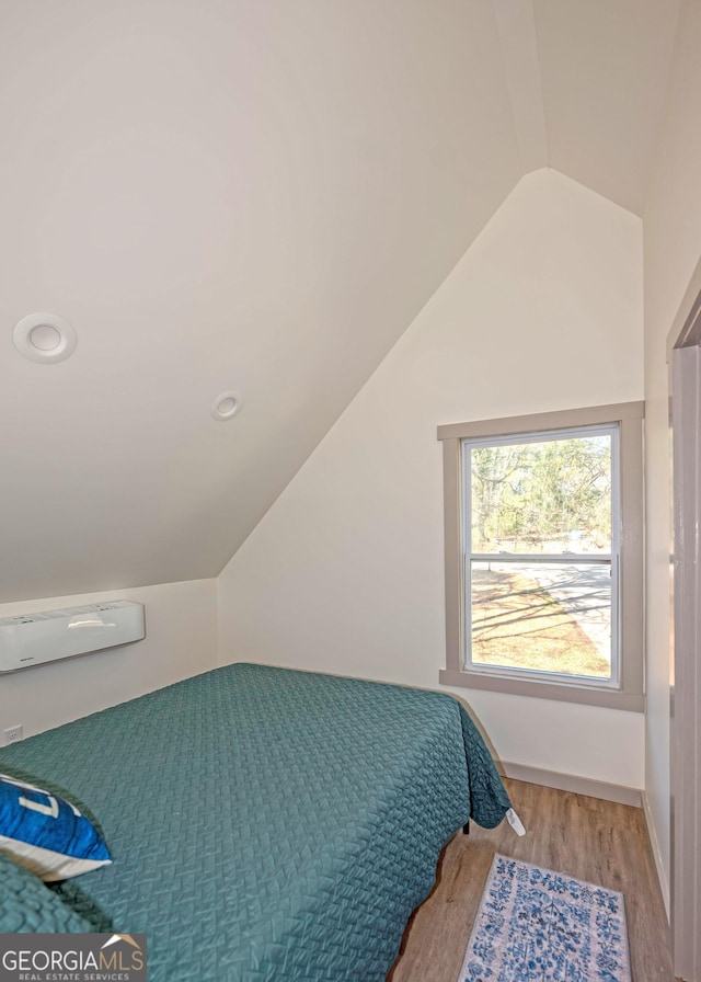 bedroom featuring light wood-style floors, baseboards, and vaulted ceiling