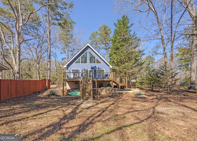 rear view of house with a deck, stairway, and fence