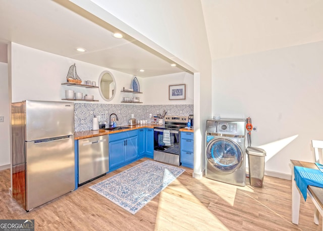 kitchen featuring washer / dryer, appliances with stainless steel finishes, blue cabinets, open shelves, and a sink