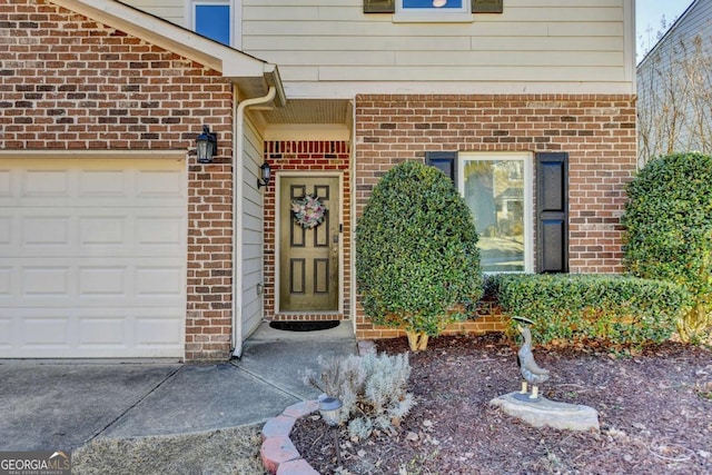 doorway to property with a garage and brick siding