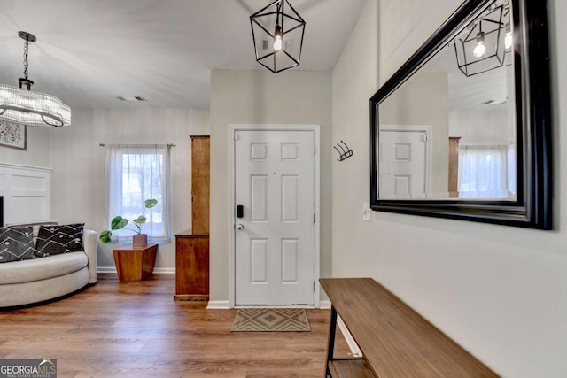 entrance foyer with an inviting chandelier, baseboards, visible vents, and wood finished floors