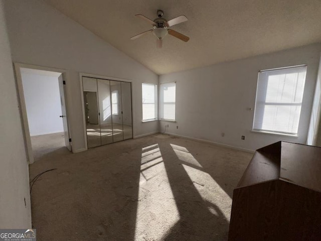 empty room with ceiling fan, high vaulted ceiling, baseboards, and light colored carpet