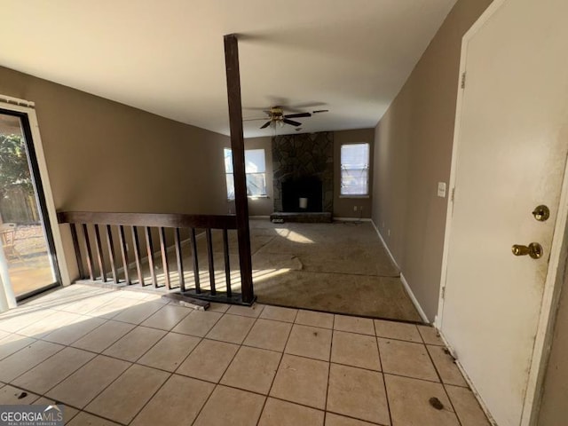 unfurnished living room with light tile patterned floors, a fireplace, baseboards, and a ceiling fan