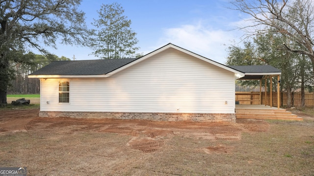 view of property exterior with roof with shingles and fence