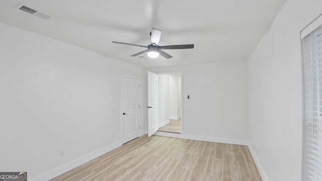 unfurnished room with a ceiling fan, light wood-type flooring, visible vents, and baseboards