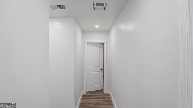 corridor featuring dark wood-style flooring, visible vents, and baseboards