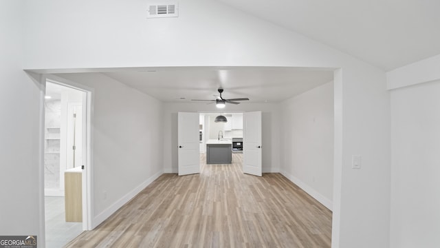 unfurnished living room with ceiling fan, baseboards, visible vents, and light wood-style floors